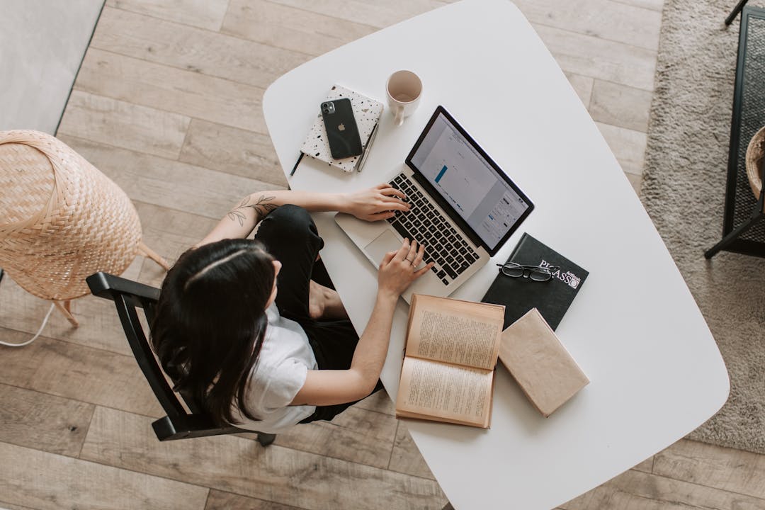 ragazza vista dall'alto seduta alla scrivania che lavora al pc