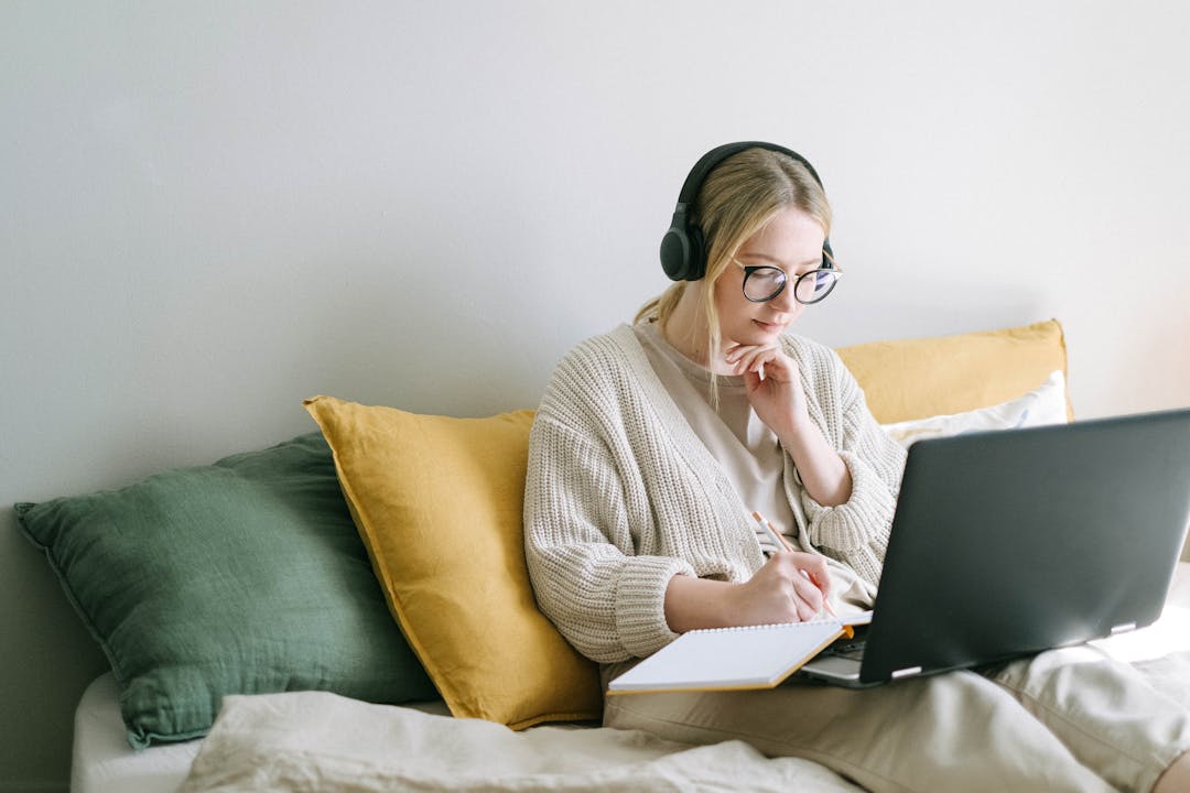 ragazza seduta sul divano che segue una lezione al pc